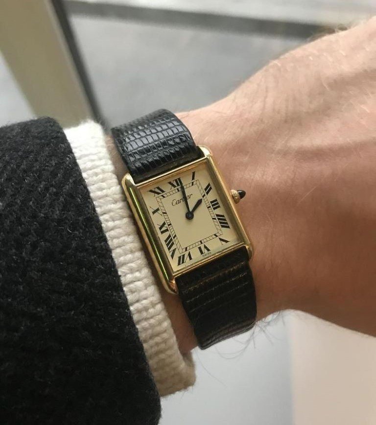 Cartier watch on a man's wrist in gold with black leather strap