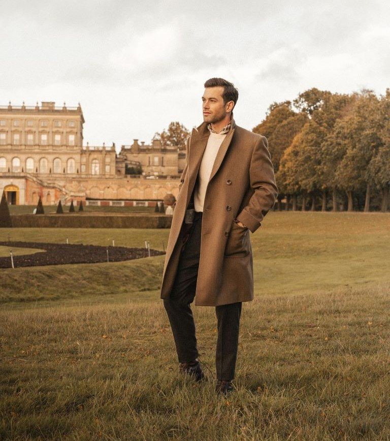 Ali Gordon in a beige overcoat on the English countryside showing the Old Money Aesthetic